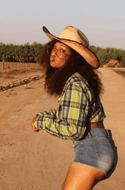 Woman In Plaid Shirt And Cowboy Hat On Dirt Road GIF