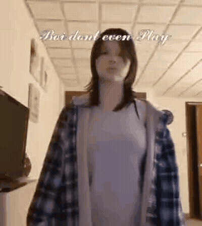 Woman In Plaid Shirt And White Shirt In Hallway GIF