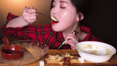 Woman In Plaid Shirt Eating Spoonful Of Food GIF