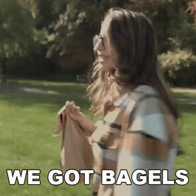 Woman In Plaid Shirt Holding Bagels Saying We Got Bagels GIF