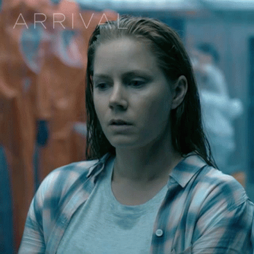 Woman in Plaid Shirt in Front of Arrival Sign
