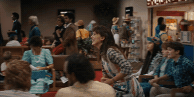 Woman In Plaid Shirt Laughing In Crowded Area GIF