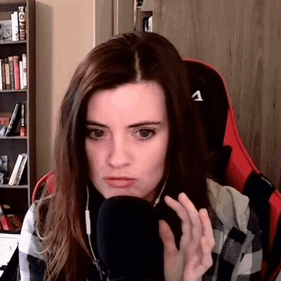 Woman In Plaid Shirt Sitting At Microphone With Letter A On Chair GIF