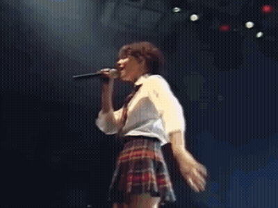 Woman In Plaid Skirt Singing On Stage GIF