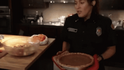 Woman In Police Uniform Holding Pumpkin Pie GIF