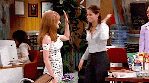Woman In Polka Dot Dress High-Fives Another In Office GIF