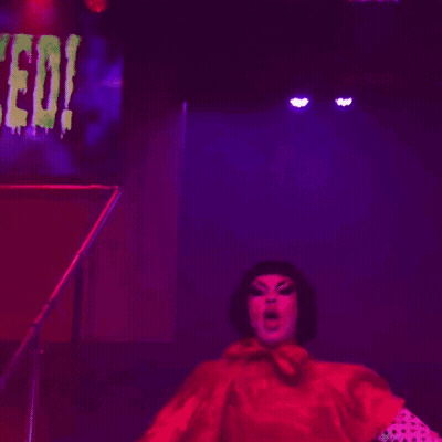 Woman In Polka Dot Gloves In Front Of Spooky Sign GIF