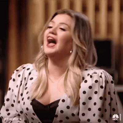 Woman In Polka Dot Shirt Singing With Mouth Open GIF