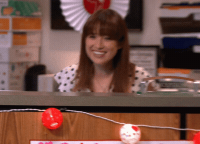 Woman In Polka Dot Shirt Smiling Behind Desk GIF