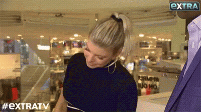 Woman In Ponytail Facing Man In Suit Extratv Sign GIF