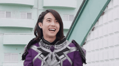 Woman in Purple and Black Outfit Smiling in Front of Building