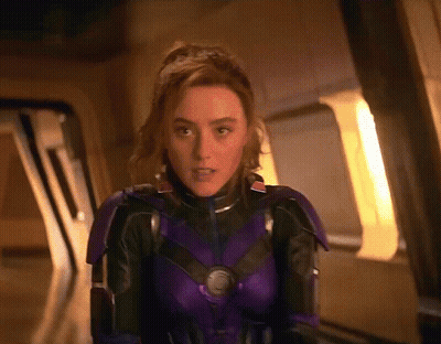 Woman In Purple And Black Suit Standing In Front Of Window GIF