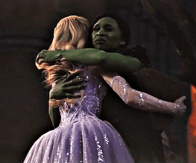 Woman In Purple Dress Hugging Woman In Green Dress GIF