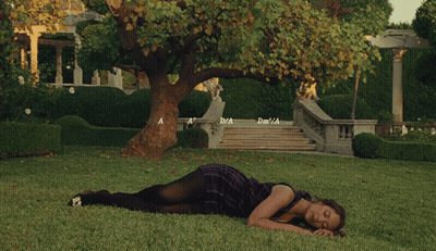 Woman In Purple Dress Lying On Grass By Tree Stairs GIF