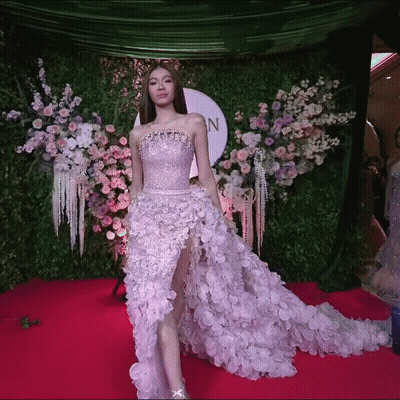 Woman In Purple Dress On Red Carpet In Front Of Flowers GIF