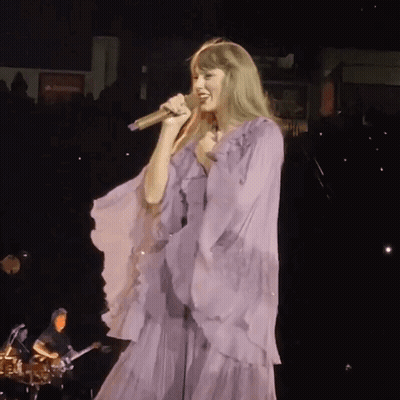 Woman In Purple Dress Singing Into Microphone On Stage GIF