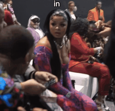 Woman in Purple Dress Sitting in Crowd With Word In