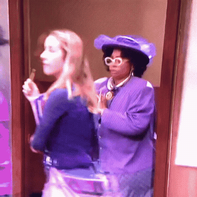 Woman In Purple Hat Next To Woman In Blue Shirt GIF