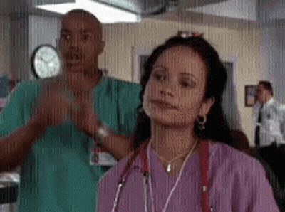 Woman In Purple Scrubs Next To Man In Green Scrubs GIF