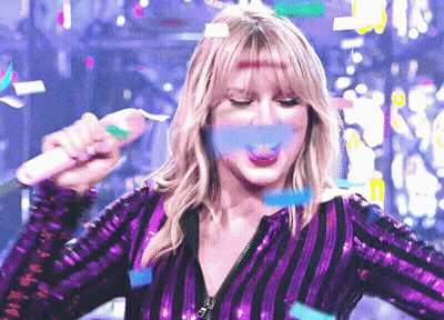 Woman In Purple Sequined Top Blowing Confetti With Microphone GIF