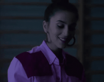 Woman In Purple Shirt And Earrings Smiling GIF