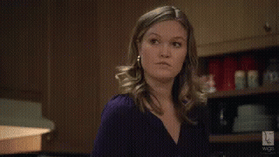 Woman In Purple Shirt And Earrings Standing In Kitchen GIF