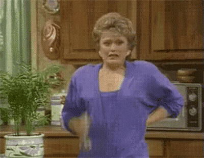 Woman In Purple Shirt Holding Towel In Kitchen GIF