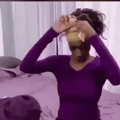 Woman In Purple Shirt Holding Yellow Object GIF