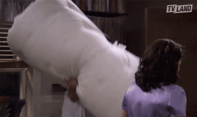 Woman In Purple Shirt Next To Man Holding TV Land Pillow GIF