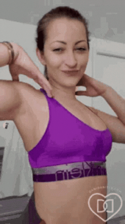Woman In Purple Sports Bra Flexing And Smiling GIF