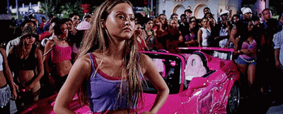 Woman In Purple Tank Top In Front Of Pink Car GIF
