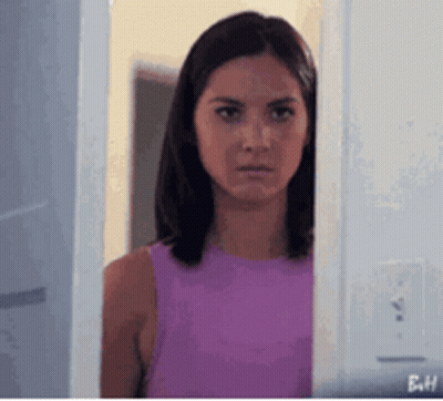 Woman In Purple Tank Top Peeking From Behind Door GIF