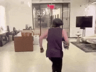 Woman in Purple Tank Top Walking Under Red Exit Sign