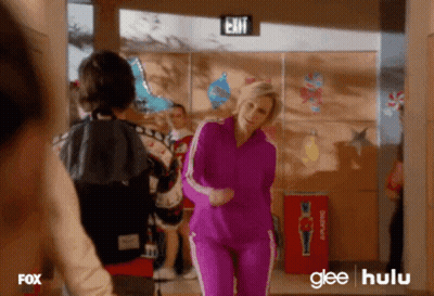 Woman In Purple Tracksuit Dancing In Hallway With Exit Sign GIF