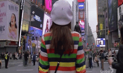 Woman In Rainbow Striped Jacket And White Hat Walking GIF