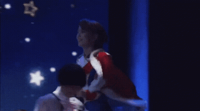 Woman In Red Coat On Stage With Blue Screen GIF