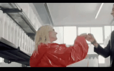 Woman In Red Coat With Man In Black Suit GIF