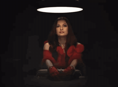 Woman In Red Dress And Red Gloves Sitting In Dark Room GIF