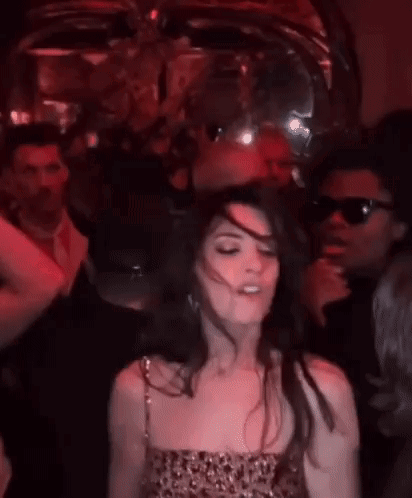 Woman In Red Dress Dancing In Dark Room With Group GIF