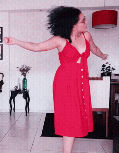 Woman In Red Dress Dancing In Living Room GIF