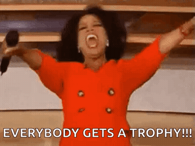 Woman In Red Dress Holding Microphone Screaming Everybody Gets A Trophy GIF