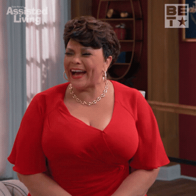 Woman In Red Dress Laughing In Front Of Assisted Living Sign GIF