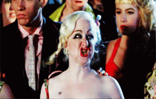 Woman In Red Dress Making Funny Face In Front Of Crowd GIF