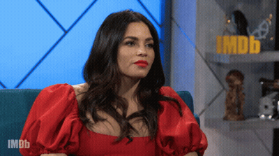 Woman In Red Dress Sitting In Front Of IMDb Sign GIF