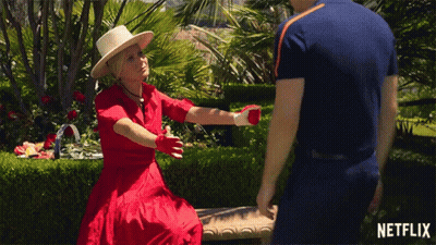 Woman In Red Dress Sitting On Bench Talking To Man GIF