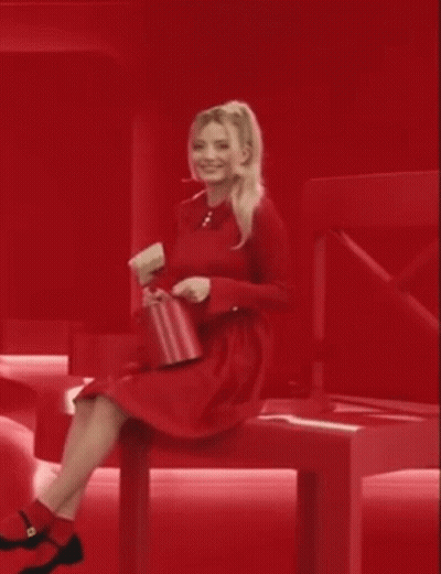 Woman In Red Dress Sitting On Red Bench Holding Red Purse GIF