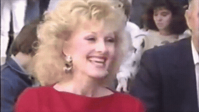 Woman In Red Dress Smiling In Crowd GIF