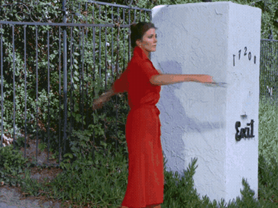 Woman In Red Dress Standing By Exit Sign GIF