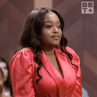 Woman In Red Dress Standing In Front Of Be Sign GIF