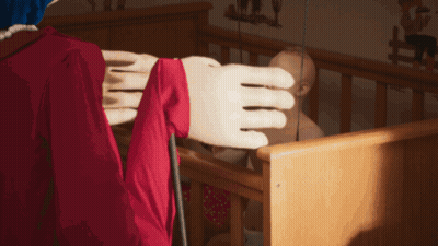 Woman in Red Dress Standing in Room With Dresser and Crib